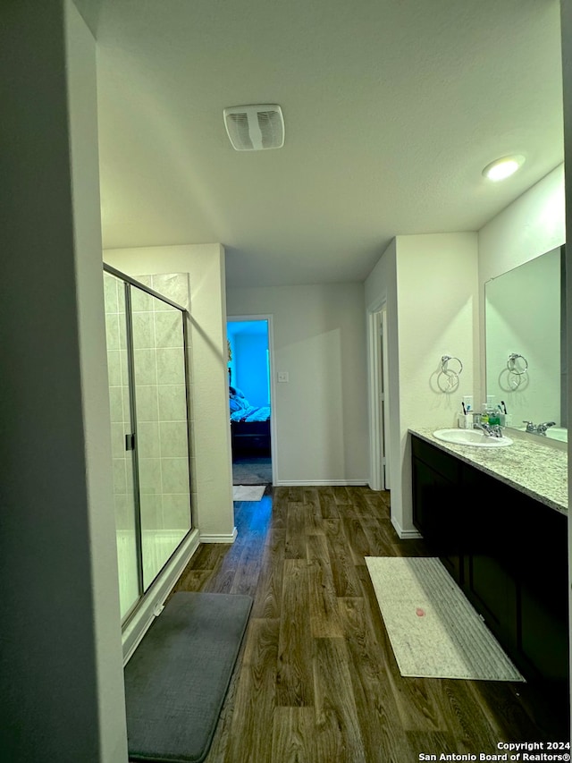 bathroom with wood-type flooring, a shower with door, and vanity