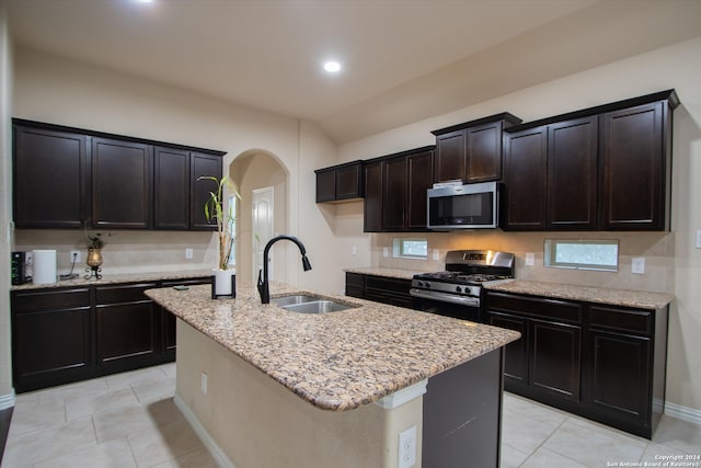 kitchen featuring light tile patterned floors, a center island with sink, appliances with stainless steel finishes, and sink