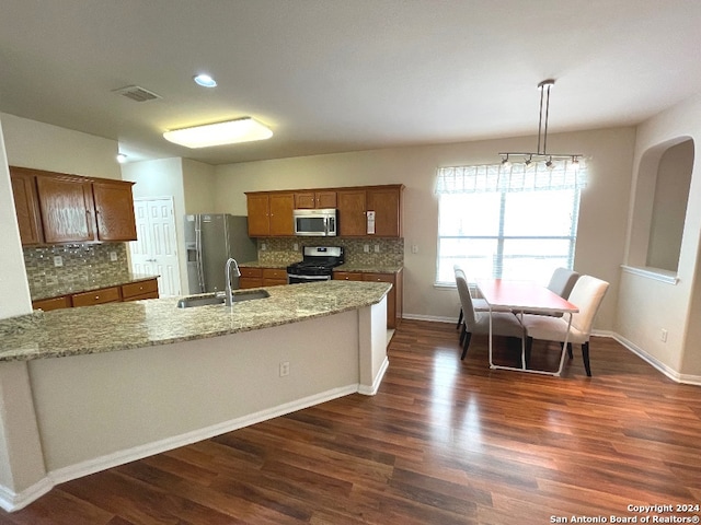 kitchen featuring appliances with stainless steel finishes, light stone counters, dark hardwood / wood-style flooring, pendant lighting, and sink