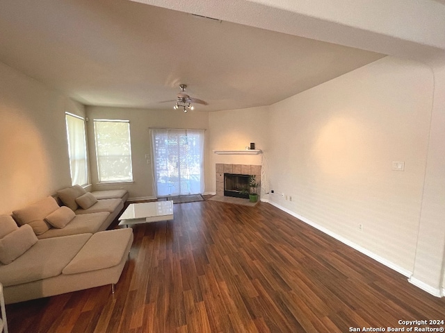 unfurnished living room with a tiled fireplace, ceiling fan, and dark hardwood / wood-style flooring