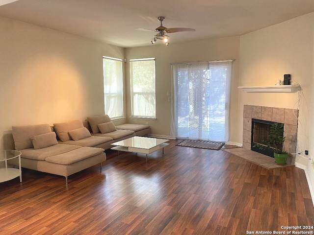 living room featuring ceiling fan, dark hardwood / wood-style floors, and a tile fireplace