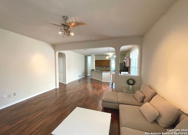 living room with ceiling fan and dark wood-type flooring