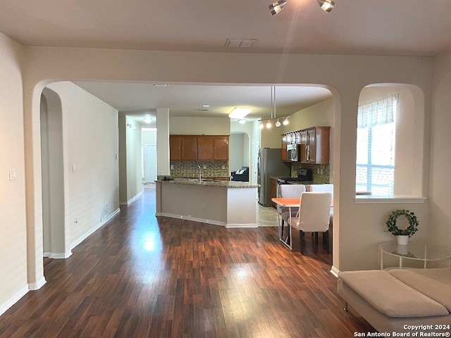 kitchen featuring hanging light fixtures, backsplash, dark hardwood / wood-style flooring, and stainless steel appliances