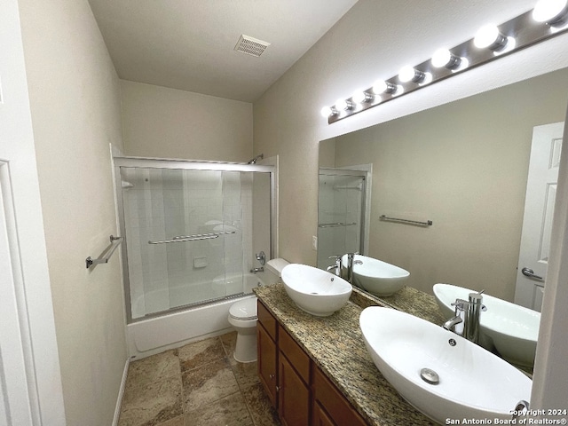 full bathroom featuring combined bath / shower with glass door, vanity, and toilet