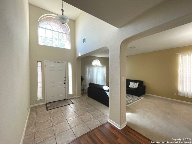 carpeted entryway featuring a towering ceiling