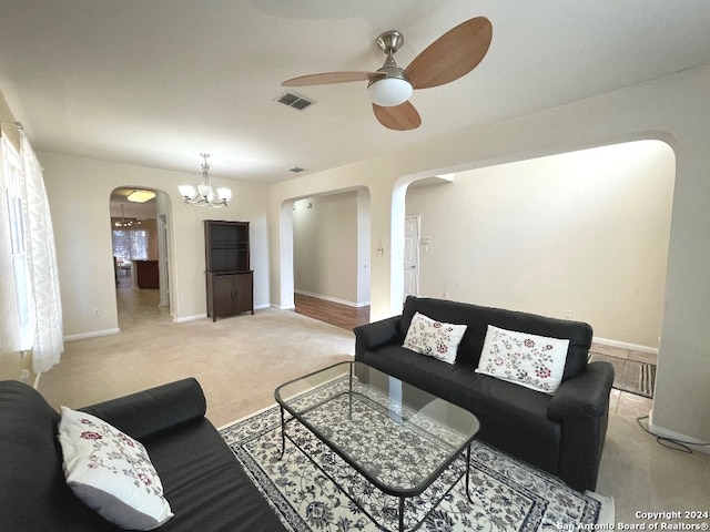 carpeted living room with ceiling fan with notable chandelier