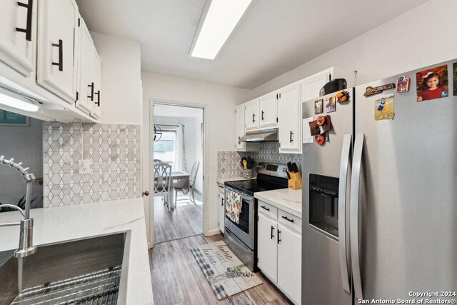 kitchen with white cabinetry, backsplash, stainless steel appliances, light hardwood / wood-style flooring, and sink