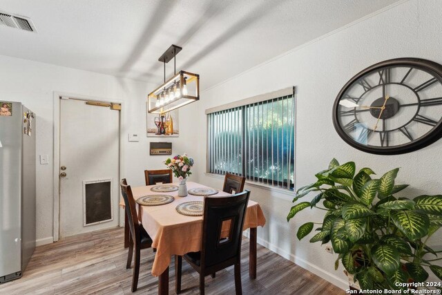 dining area with hardwood / wood-style flooring, lofted ceiling, a chandelier, and ornamental molding