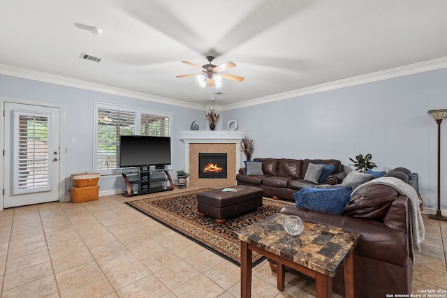 living room with a tiled fireplace, ceiling fan, and crown molding