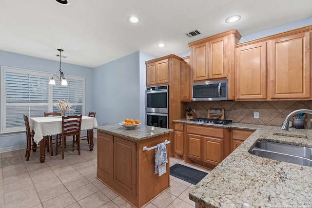 kitchen with hanging light fixtures, tasteful backsplash, stainless steel appliances, a center island, and sink