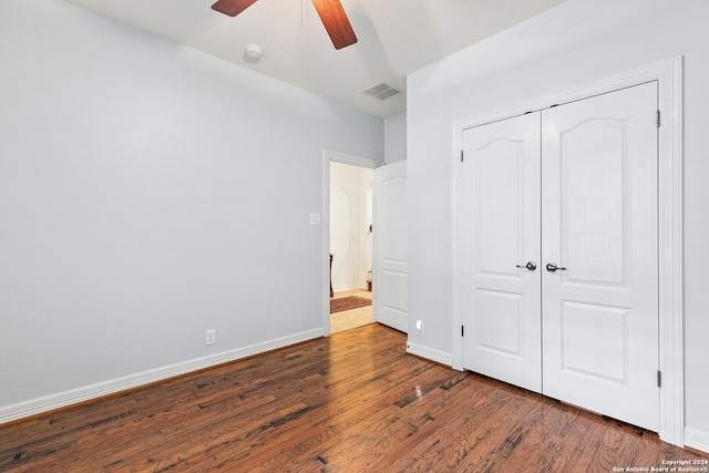 unfurnished bedroom featuring ceiling fan, a closet, and dark wood-type flooring