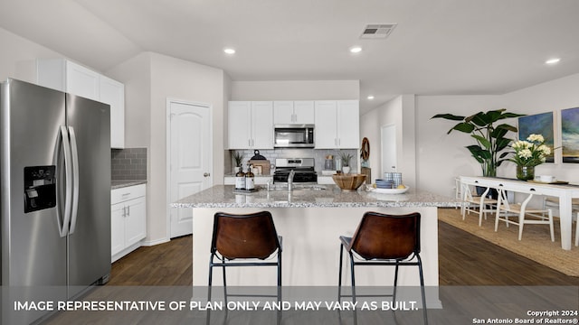 kitchen featuring tasteful backsplash, an island with sink, white cabinets, appliances with stainless steel finishes, and dark hardwood / wood-style flooring