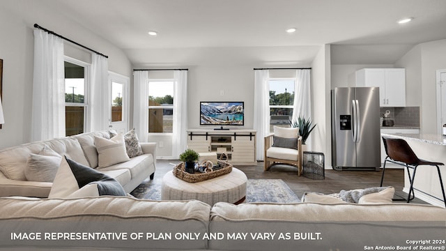 living room featuring a wealth of natural light, vaulted ceiling, and dark hardwood / wood-style floors