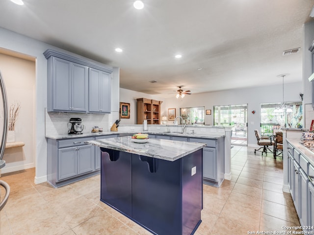 kitchen featuring a kitchen breakfast bar, kitchen peninsula, a kitchen island, ceiling fan, and sink