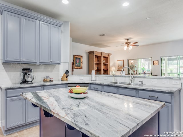 kitchen featuring ceiling fan, sink, kitchen peninsula, and a center island