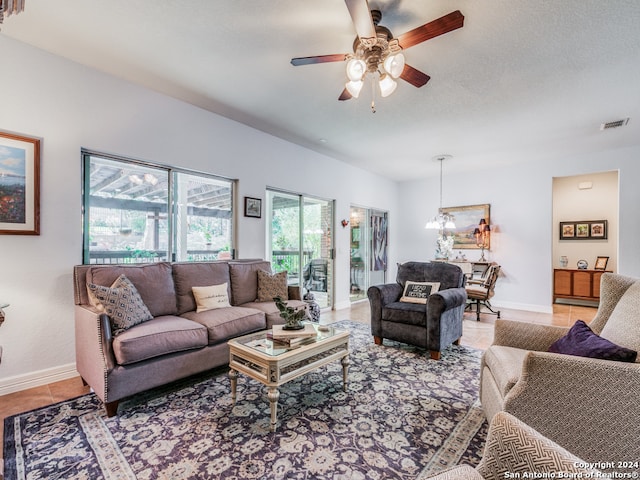 living room with ceiling fan with notable chandelier and light tile patterned floors