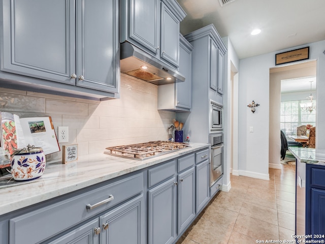 kitchen with a notable chandelier, decorative backsplash, appliances with stainless steel finishes, and light tile patterned flooring