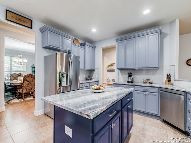 kitchen featuring decorative backsplash, blue cabinetry, stainless steel appliances, an inviting chandelier, and a center island