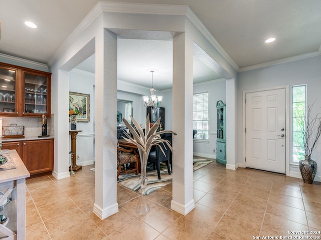 tiled entrance foyer with bar area, an inviting chandelier, and ornamental molding