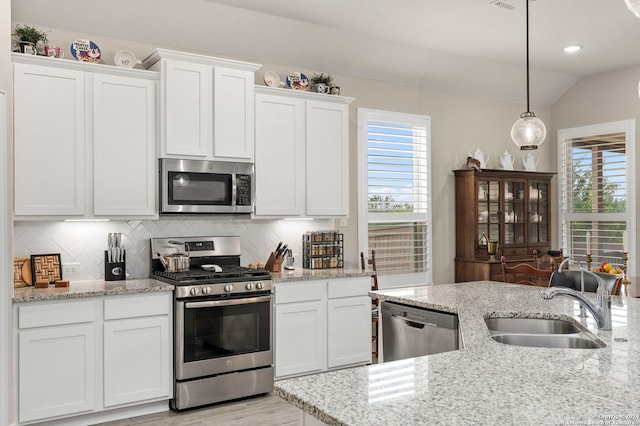 kitchen with hanging light fixtures, white cabinetry, stainless steel appliances, lofted ceiling, and sink