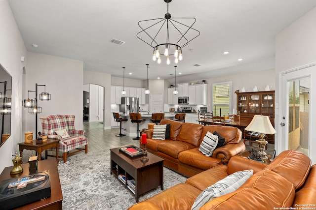 living room with light wood-type flooring and a notable chandelier