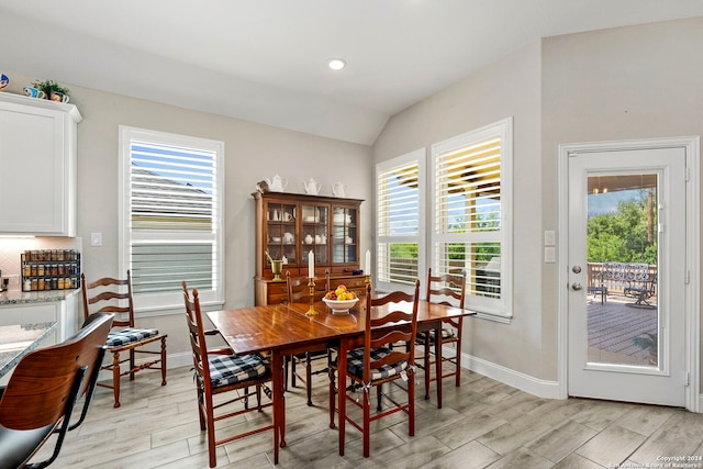 dining space with vaulted ceiling and light hardwood / wood-style floors