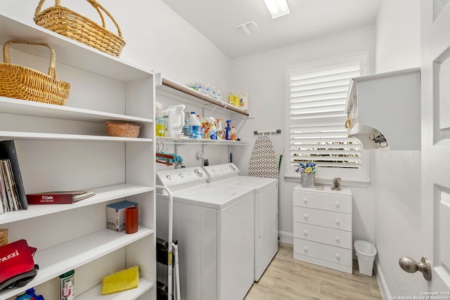 clothes washing area with washer and clothes dryer and light wood-type flooring