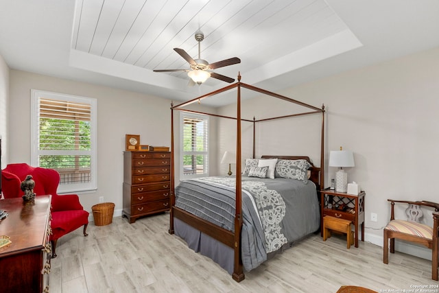 bedroom featuring ceiling fan, a tray ceiling, and light hardwood / wood-style floors