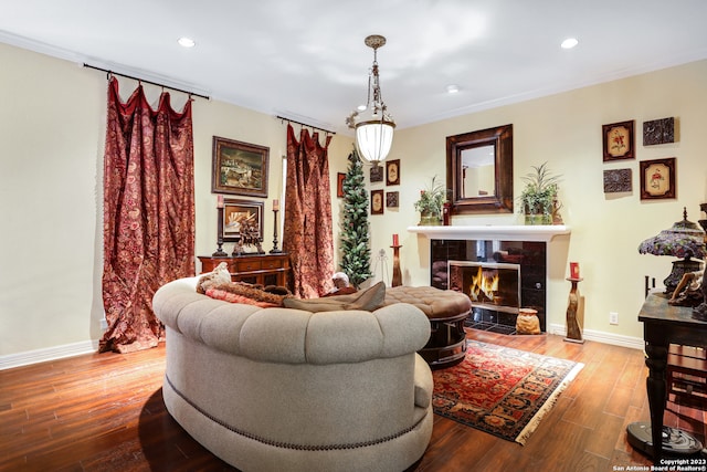 living room featuring ornamental molding, a tiled fireplace, and hardwood / wood-style flooring