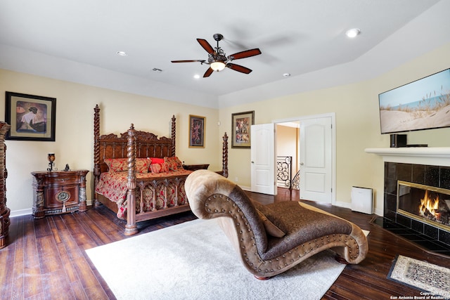 bedroom featuring ceiling fan, a fireplace, and dark wood-type flooring