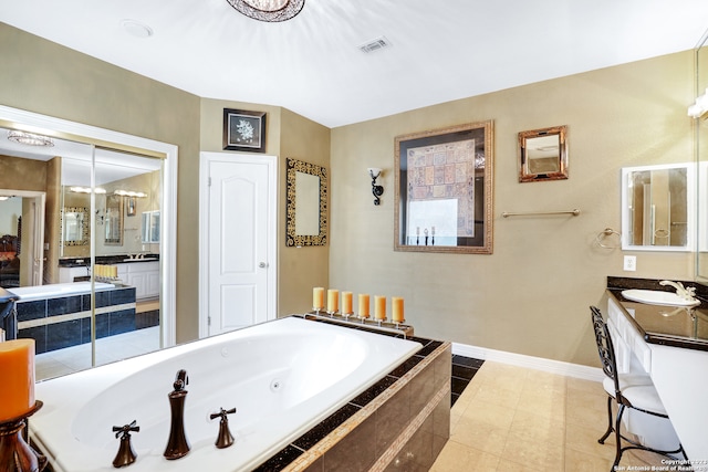 bathroom with tiled tub, vanity, and tile patterned flooring