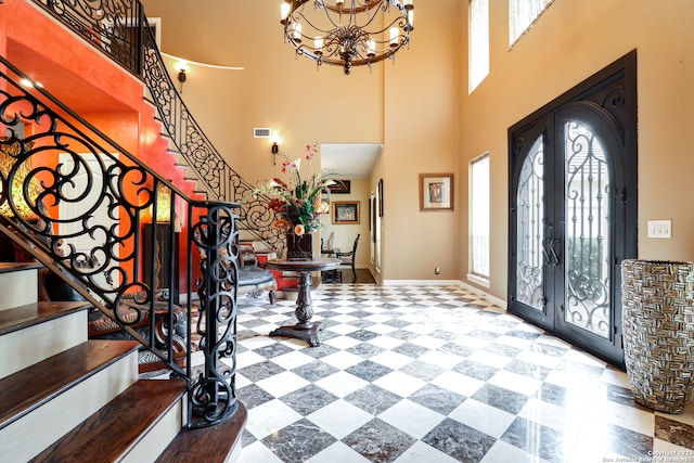 foyer entrance featuring french doors, an inviting chandelier, and a towering ceiling