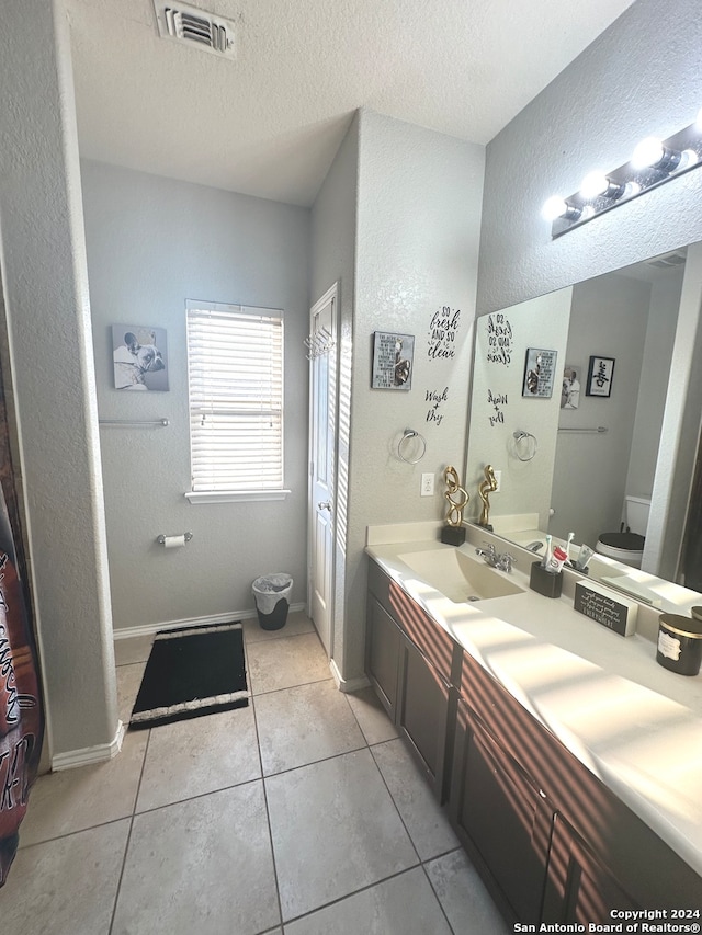 bathroom featuring toilet, a textured ceiling, vanity, and tile patterned floors