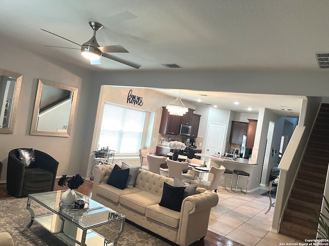 living room featuring light tile patterned floors and ceiling fan with notable chandelier