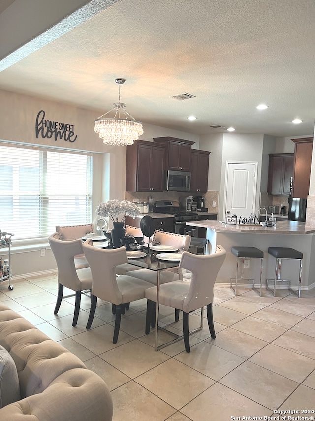 tiled dining room featuring a notable chandelier, a textured ceiling, and sink