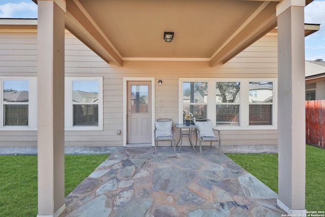 entrance to property featuring a patio and a yard