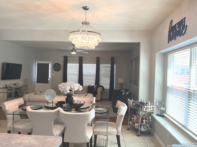 tiled dining space with ceiling fan with notable chandelier