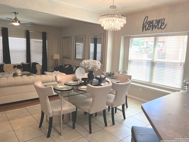 dining space with light tile patterned floors and ceiling fan with notable chandelier