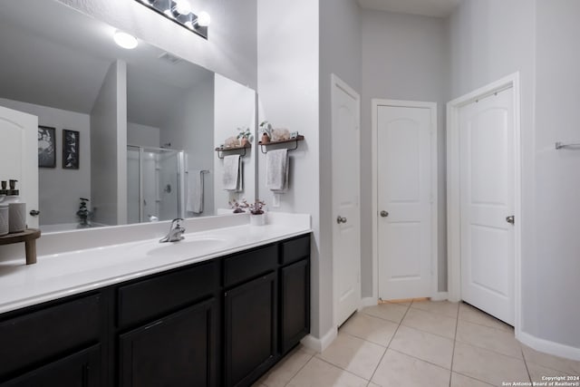 bathroom with tile patterned floors, a shower with door, and vanity