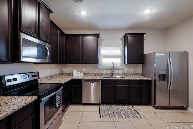 kitchen featuring dark brown cabinetry, sink, light tile patterned floors, and stainless steel appliances