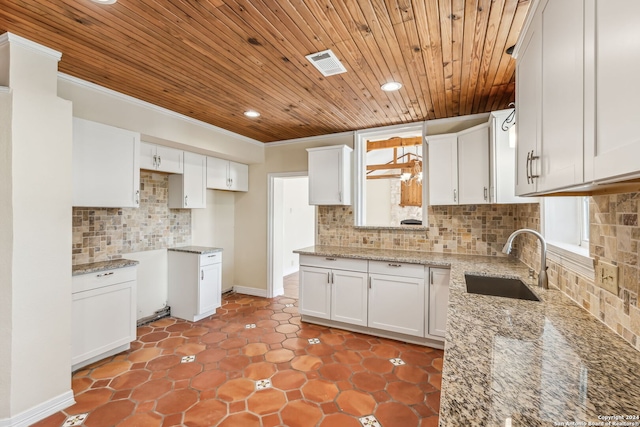 kitchen with backsplash, white cabinetry, light stone counters, and sink