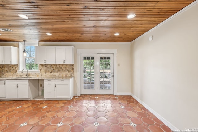 kitchen featuring hanging light fixtures, a healthy amount of sunlight, and white cabinetry