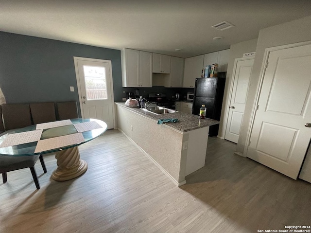 kitchen featuring white cabinets, kitchen peninsula, light wood-type flooring, sink, and black fridge