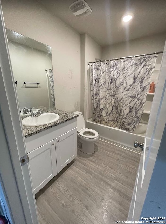 full bathroom featuring shower / tub combo with curtain, wood-type flooring, vanity, and toilet