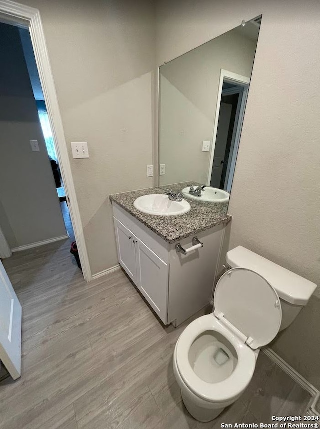 bathroom featuring wood-type flooring, vanity, and toilet