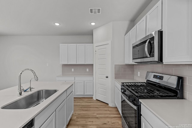 kitchen with sink, stainless steel appliances, tasteful backsplash, light hardwood / wood-style flooring, and white cabinets