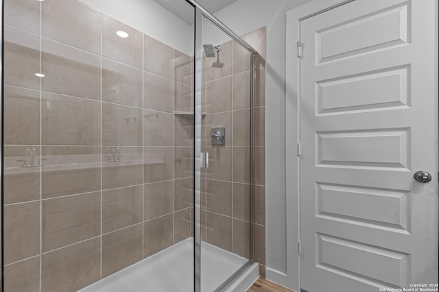 bathroom with a shower with door and wood-type flooring