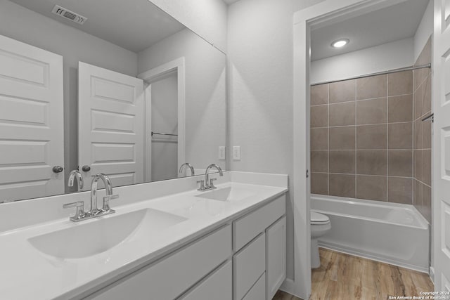 full bathroom featuring toilet, vanity, tiled shower / bath combo, and hardwood / wood-style flooring