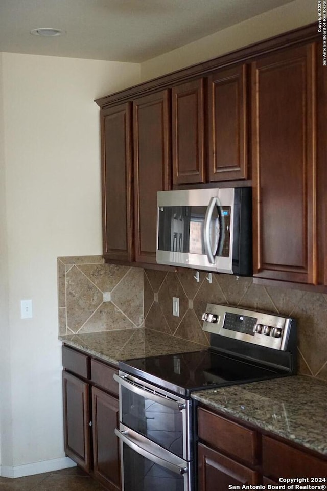 kitchen with appliances with stainless steel finishes, stone counters, and tasteful backsplash