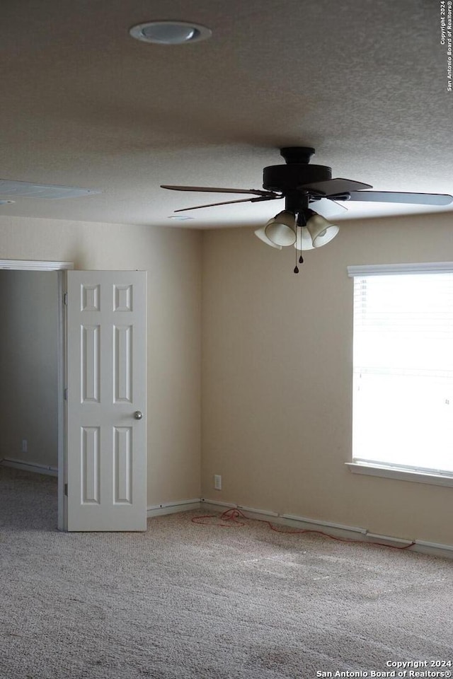 carpeted empty room featuring ceiling fan and a textured ceiling